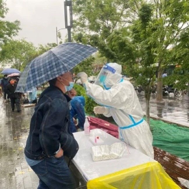 图为医务人员在雨中为群众进行核酸采集