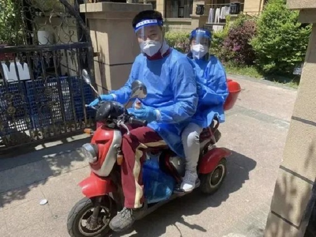 图为王彦章身穿防护服参与志愿服务