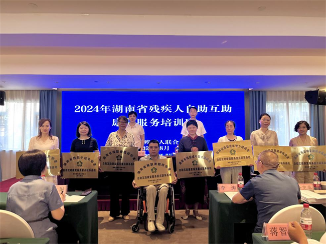 图为金新娟及省残联康复部相关负责人为8家自助互助康复服务基地进行授牌