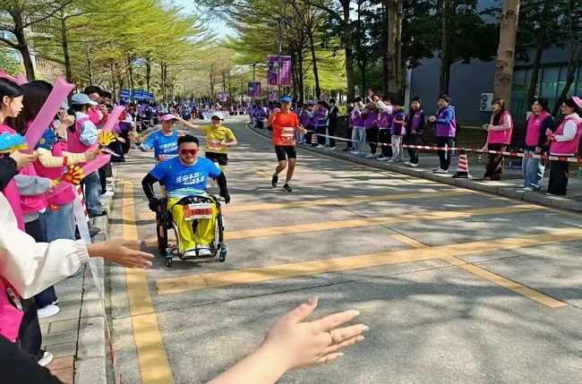 图为沿途观众为肢体残障跑者加油鼓劲