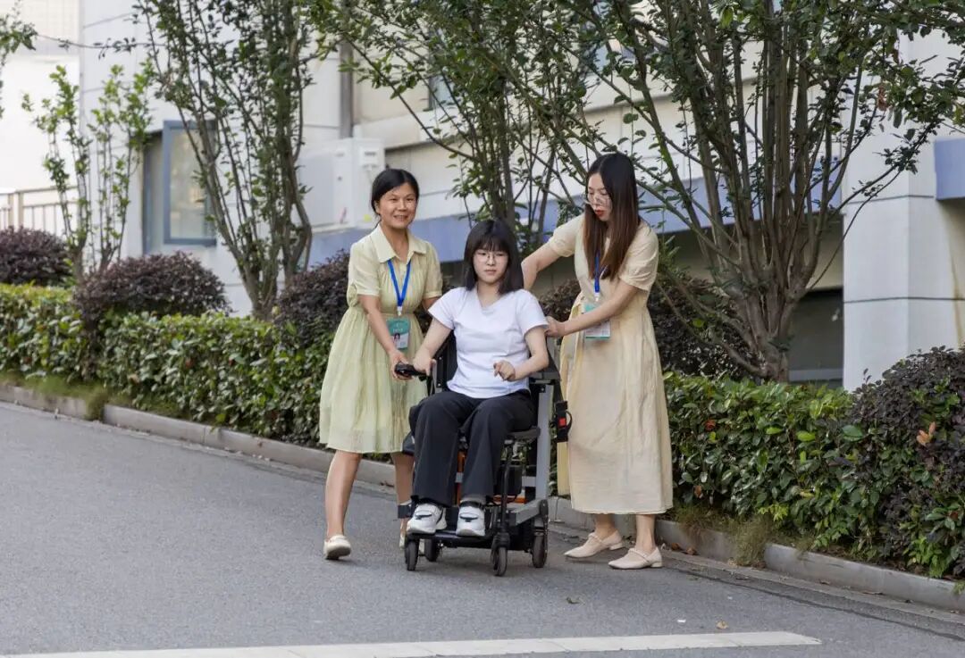 图为曹慧婷在妈妈张胜兰(左)和送考老师的帮助下,坐着轮椅“走”出考场 图为曹慧婷在妈妈张胜兰(左)和送考老师的帮助下,坐着轮椅“走”出考场